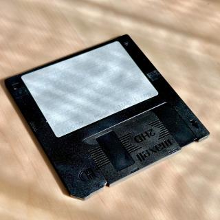 One floppy on a table with the label applied. The label has check boxes for different formats - DOS/V, Mac, PC98, Other