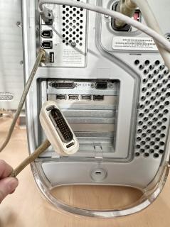 The rear of a PowerMac G4 and a plug that resembles DVI but had rounded corners 