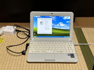 A small white laptop hooked up to a USB-C power supply running Windows XP with the about this computer screen open showing an Intel Atom CPU @ 1.6 GHz and 2 GB of RAM