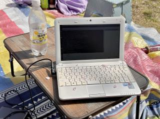 A small white laptop on a camping table with sakura petals having fallen on the keyboard 