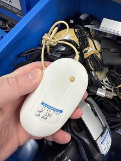 An Apple Mighty Mouse - a white, featureless mouse with a small (yellowed) trackball. The price tag says 330 yen.