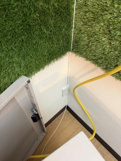 The corner of a room showing a white fiber cable going from the ceiling into an outlet and then another cable going out from it