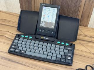 The Palm in a keyboard stand that says GoType!There are bright teal function keys that betray the era of design