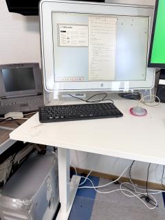 A PowerMac G4 QuickSilver sits on the floor, on the desk is a “huge” 22” wide screen Cinema Display