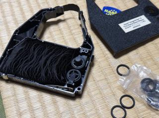 A dot matrix ribbon taken apart. There are rubber washers strewn about