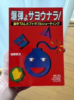 A red book with an illustration of a bomb on it and the text 爆弾ょサヨウナラ！