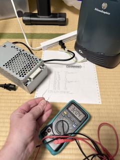 A paper clip being held up menacingly in front of a printout of the power supply pin out.