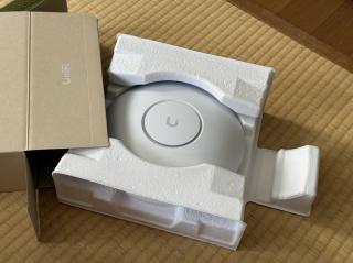 A round white disc with a U logo coming out of a box thst says UniFi on it
