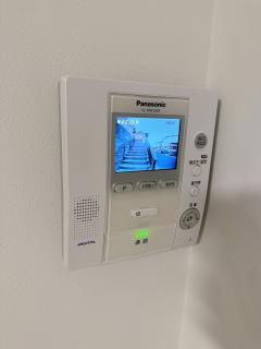 A Panasonic door intercom showing a video feed of outside