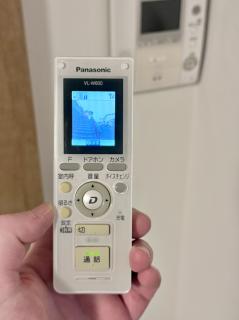 A Panasonic VL-W600 handset which looks kind of like and old-school cordless phone. Some of the buttons are slightly yellowed. On the display it it is showing a picture of the outside.