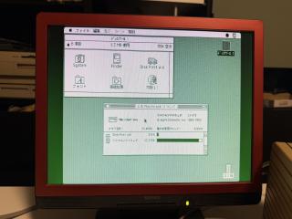 A photo of a computer monitor showing a black and white screen of Macintosh System 6 showing the about this Mac screen. The whole screen has a green tint.