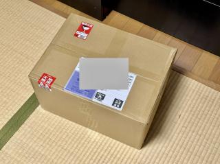 A sealed cardboard box on the floor with fragile stickers 