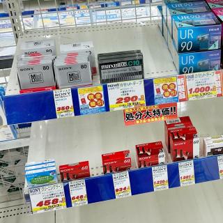 A shelf in an electronics store with various obsolete blank media - minidisc, cassette tape and miniDV tape