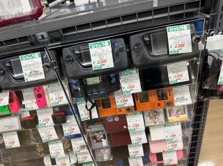 A rack of old handheld consoles: Sega Game Gear, Game & Watch, etc