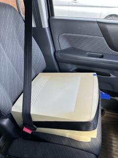 A PowerMac 7600 strapped into a car with a seatbelt 