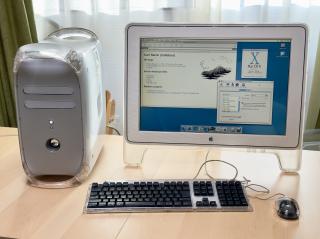 A PowerMac G4 Quicksilver set up with a 22 graphite Apple Cinema Display and the Apple Pro Keyboard and Mouse on a wood laminate table with the evening sun coming in through the window 