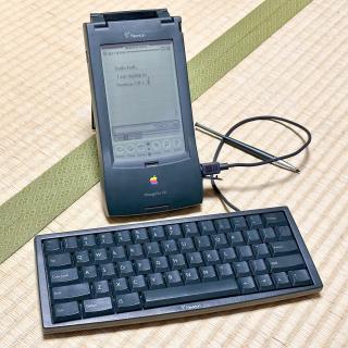 A Newton 120 running Newton OS 1.3 with a Newton Keyboard plugged into it, with a note on the screen saying Hello fedi, I'm typing in Newton OS 1.3. A text input bar set to 英語 is visible at the bottom of the screen.