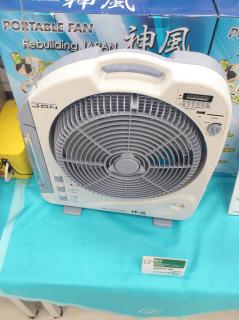 A box fan with an antenna, CFL lights, and an MP3 Player.The box is seen in the background with the name 神風 and Rebuilding Japan