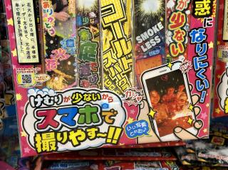 A colorful multi-pack of sparklers with japanese writing on it. And a graphic of a person taking a photo of their kids on a smartphone.けむりが少ないからスマホで撮りやす!!