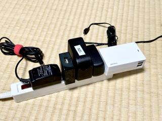 A power strip with 5 different AC/DC adapters all with different sizes snugly butted up against each other