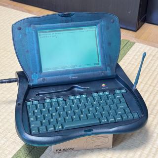 An Apple eMate 300 in an opened position with the backlight on and wow this is neat written on the screen