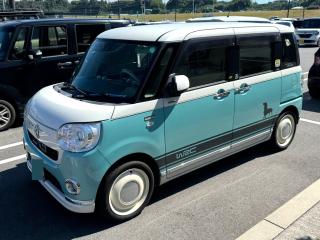 A small kei car with two tone white and teal. The front has a VW emblem in the center, the side has a decal that says WRC. It has white steel wheels.