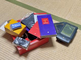 Original Newton MessagePad box contents - battery pack, charger, getting started VHS tape, and two original Newtons with completely messed up LCD displays
