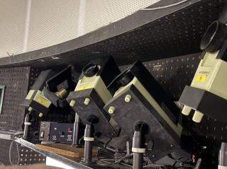 Four “color CABIN-II”-branded compact slide projectors aimed upwards, ready to show the constellations. The one in the rear is pointed at a mirror pointed toward it, revealing a motor on the read of it with a controller box with speed and reverse