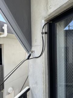 Two black wires bolted to the side of a building