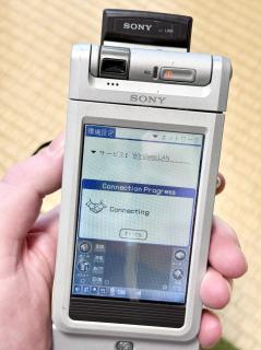 A Sony Clie with a black lump sticking out the back top. On the display it is Connecting to Wireless LAN