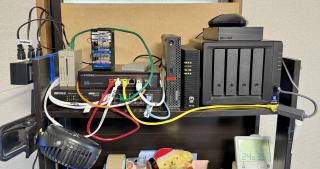 A shelf with two switches, a ThinkCentre, a 10G-ONU, a Synology NAS, and lots of cables on it
