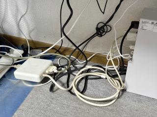 The floor with lots of cable spaghetti, a PC, and a big square plastic box with an Apple logo on it and thick cables coming out