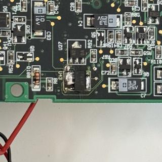 A small chip with globs of solder on the pins.