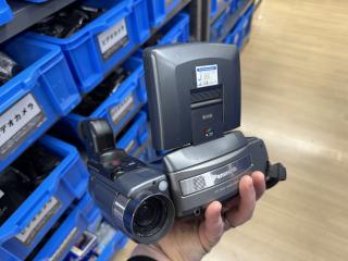 A hand holding a silver device that says Panasonic LCD Video Camera. It has a large video lens on the side with a viewfinder and a large flip-up LCD