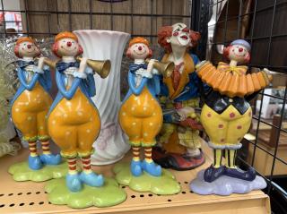 Four creepy ceramic clown statues. Three are holding horns, one an accordion and one is wearing a tramp outfit