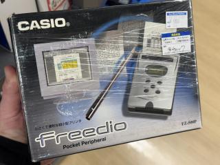 The front of a box that says CASIO freedio Pocket Peripheral FZ-500PThere is a picture of a CRT showing a word document and the document is morphing over to a small silver device with a one-line monochrome text LCD that says PRINTING and a receipt paper with a spreadsheet is coming out of it.550 yen