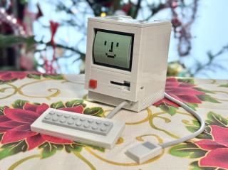 A photo of a completed LEGO-style building brick set of a classic Macintosh showing the smiley face boot icon