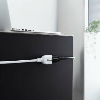 The extension cord in use, you can see the exposed earth prong. This picture also shows off the magnetic feature with the plugs stuck to the side of a desk