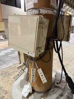 A plastic box strapped to a pole with 5 wires with outlets dangling from it