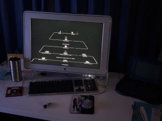 A photo of a dark room with a an old Apple 20 Studio Display showing a screen saver