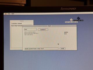 a photo of an LCD screen showing a system 7 application named MacOS Toolbox 68k with some buttons and text fields labeled Connect and send haphazardly strewn about. there are chat messages:hello world from qemuhello world from mac iicx!User went online