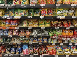 Shelves full of colorful Japanese snacks, except in the middle are some silver black and white packages