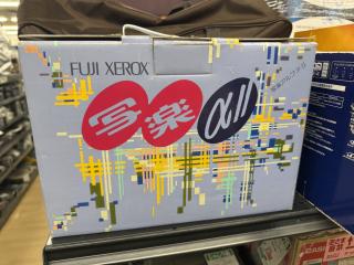 A box with glitchy art and 90's fonts that says FUJI XEROZ 写真αII (写真αＩＩ)