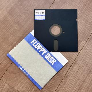 A black 5.25-inch floppy marked Disk no‘86.1.22FLOPPY DISK2DDTOPPAN MOOREpartially inside a sleeve that saysFLOPPY DISKTOPPAN MOORE