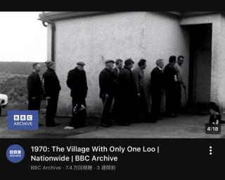 A screenshot of a YouTube Thumbnail for a BBC Archive video titled “1970: The Village With Only One Loo |Nationwide | BBC Archive”The image is a black and white still of a line of men waiting on a toilet