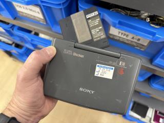 A hand holding a Sony DATA Discman DD-20 Electronic Book Player EBXA Electronic Book. A gray plastic clamshell device, with a 330 yen price tag on it. In the back is also a disc caddy