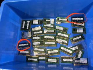 A blue bin full of laptop RAM. Two sticks are circled in red.