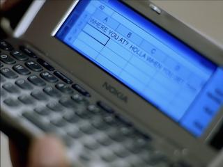 A Nokia Communicator with a spreadsheet open with the text “WHERE YOU AT? HOLLA WHEN YOU GET H” written in cell A1